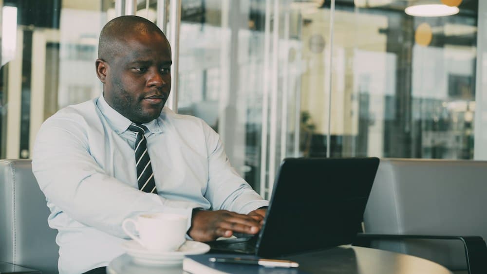 Profissional de camisa e gravata analisando informações no notebook